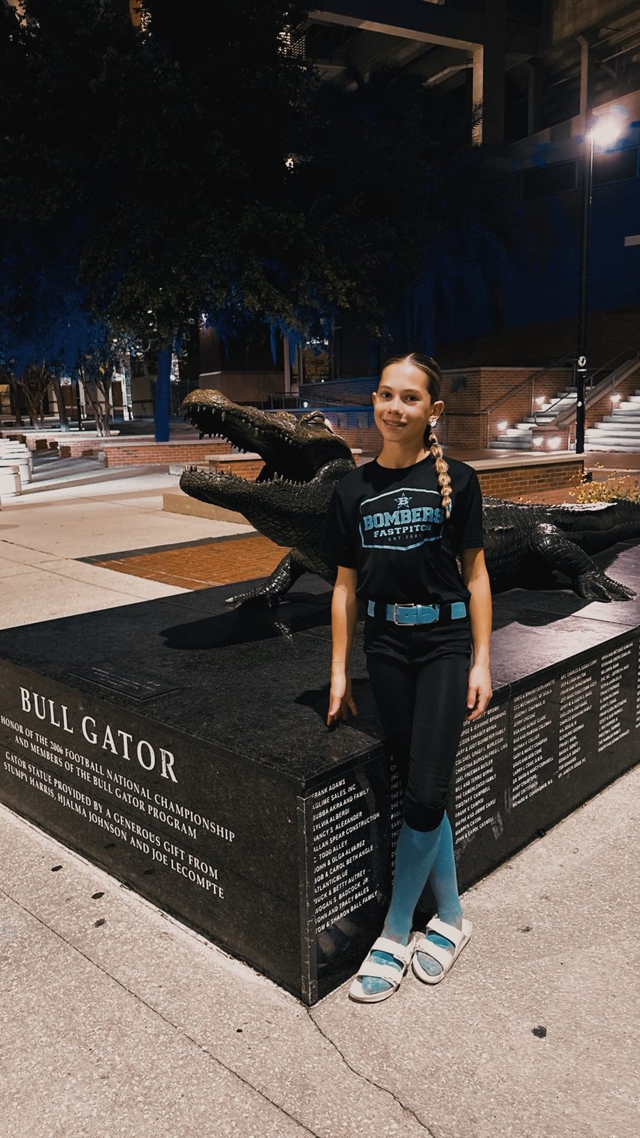 Camden in a Bombers Fastpitch shirt beside the Bull Gator statue at the University of Florida