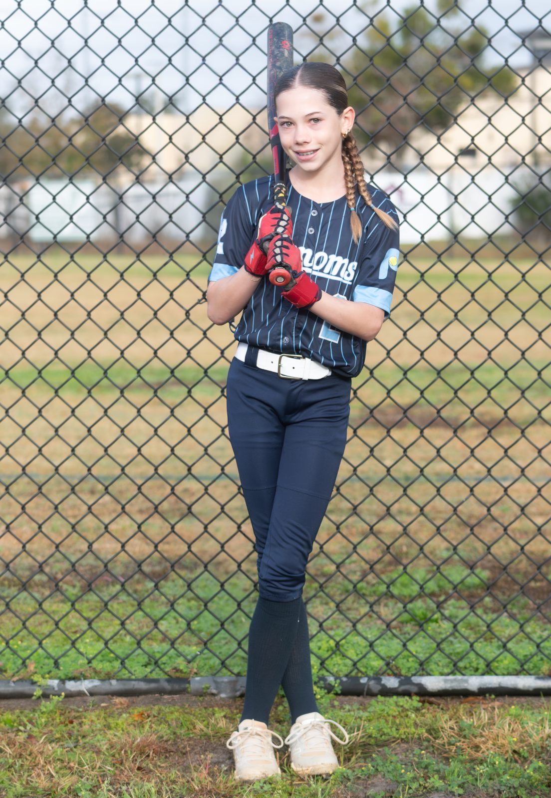 Camden holding a bat at the ready in a navy pinstripe Phenoms uniform