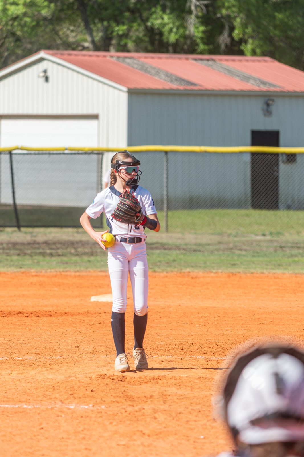 Camden on the pitching circle in a white uniform, ball in hand