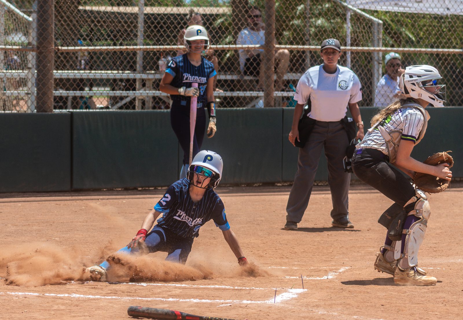 Camden sliding into home plate in a cloud of dust as the catcher takes the throw